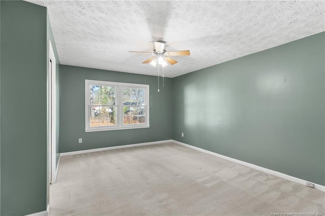 empty room featuring a textured ceiling, light colored carpet, and ceiling fan