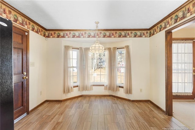 unfurnished dining area featuring light wood-type flooring, an inviting chandelier, and crown molding