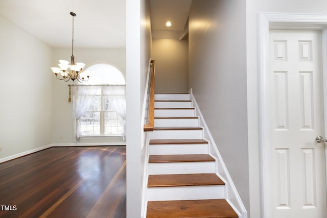 stairs featuring hardwood / wood-style flooring and an inviting chandelier