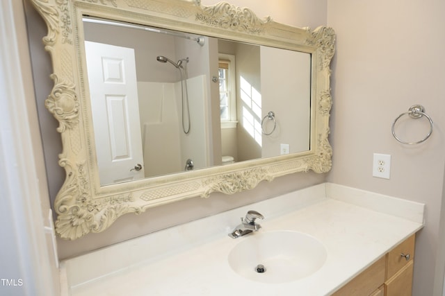 bathroom featuring a shower, vanity, and toilet