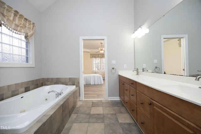 bathroom featuring tiled bath, ceiling fan, vanity, and a healthy amount of sunlight