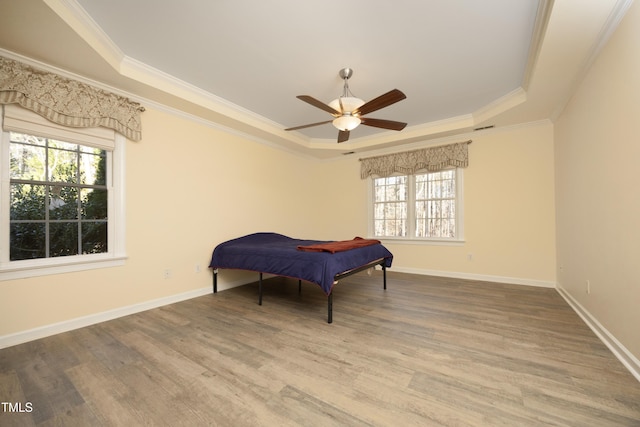 bedroom featuring multiple windows, a tray ceiling, and ceiling fan