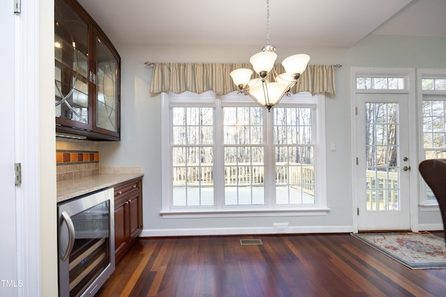 unfurnished dining area featuring bar, wine cooler, dark hardwood / wood-style flooring, and a notable chandelier