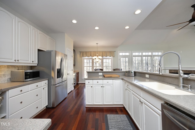 kitchen with white cabinetry, sink, hanging light fixtures, ceiling fan with notable chandelier, and appliances with stainless steel finishes