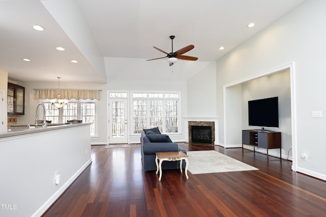 living room with dark hardwood / wood-style flooring, ceiling fan with notable chandelier, high vaulted ceiling, and sink