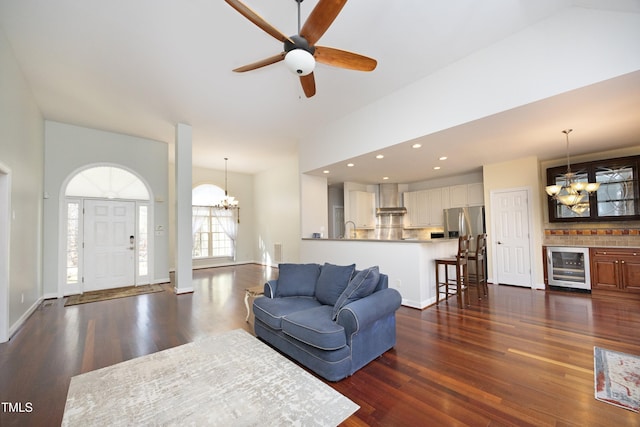 living room with dark hardwood / wood-style flooring, beverage cooler, ceiling fan with notable chandelier, and sink