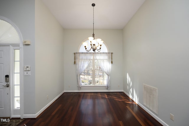 unfurnished dining area with dark hardwood / wood-style flooring and a chandelier