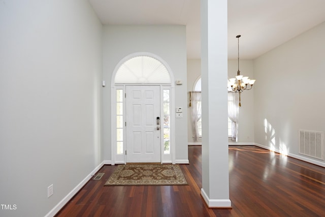 entrance foyer with a notable chandelier, plenty of natural light, dark hardwood / wood-style floors, and a towering ceiling