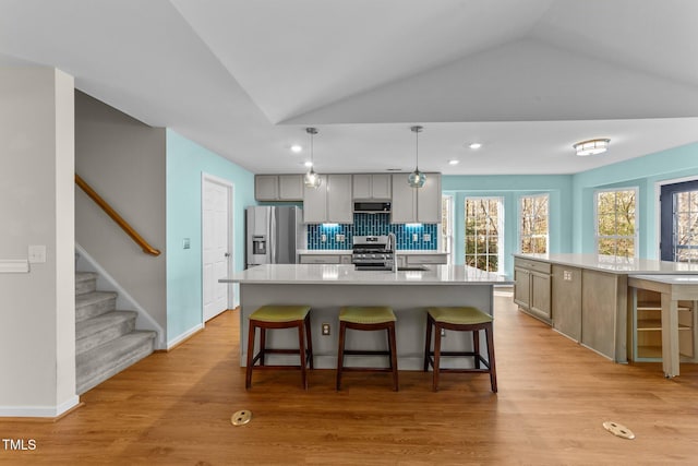 kitchen featuring light hardwood / wood-style flooring, a spacious island, stainless steel appliances, and tasteful backsplash