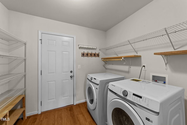 laundry room featuring washing machine and clothes dryer and light hardwood / wood-style flooring