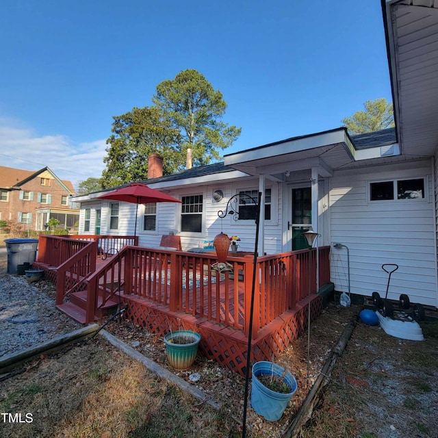 rear view of house featuring a chimney and a wooden deck