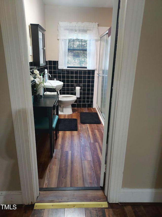 full bath featuring tile walls, toilet, a stall shower, vanity, and wood finished floors