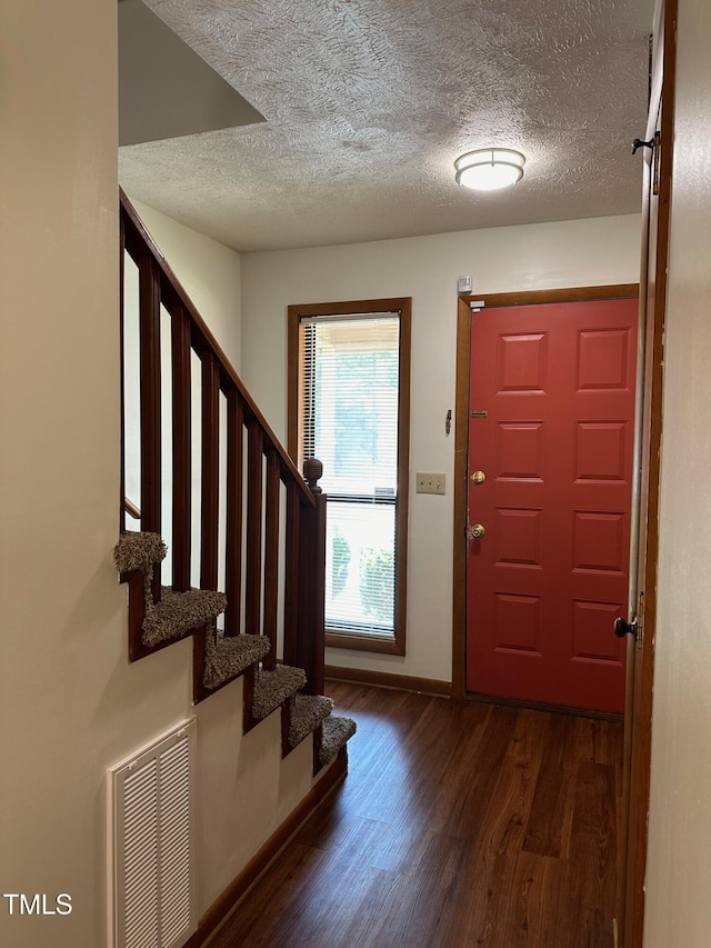 entrance foyer with a textured ceiling and dark hardwood / wood-style floors