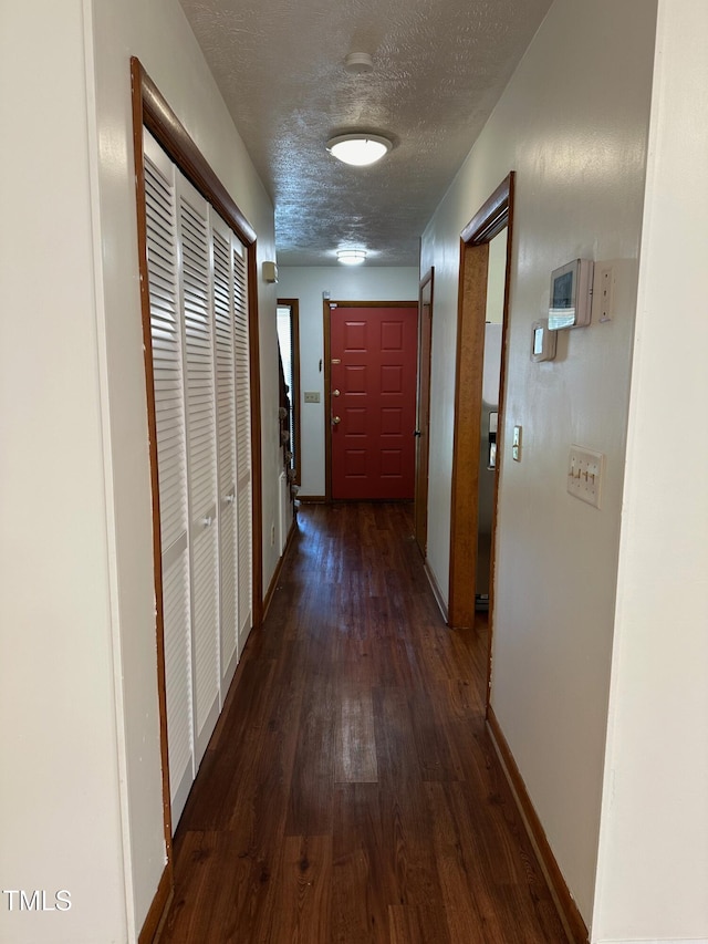 corridor featuring dark hardwood / wood-style flooring and a textured ceiling