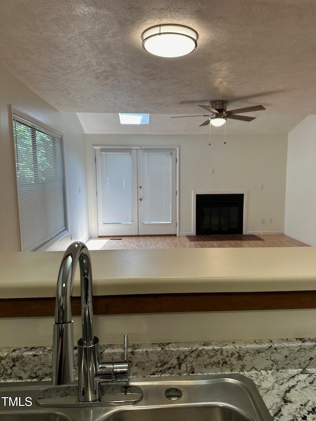 interior details with ceiling fan, sink, and a textured ceiling