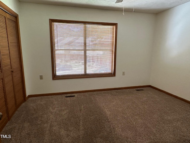 carpeted spare room featuring ceiling fan