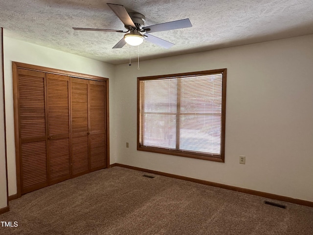 unfurnished bedroom with carpet flooring, ceiling fan, a closet, and a textured ceiling