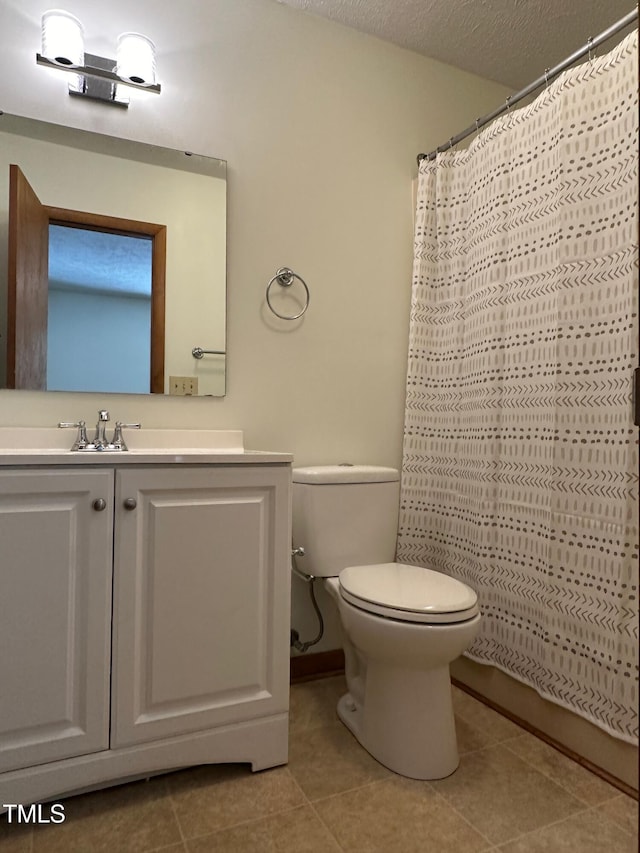 bathroom with tile patterned floors, walk in shower, a textured ceiling, vanity, and toilet