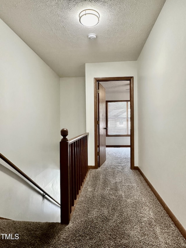 corridor with carpet and a textured ceiling