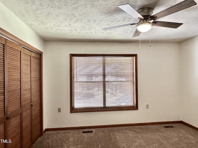 unfurnished bedroom featuring carpet flooring, ceiling fan, a closet, and a textured ceiling