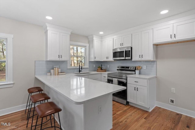 kitchen featuring appliances with stainless steel finishes, sink, white cabinets, and a breakfast bar