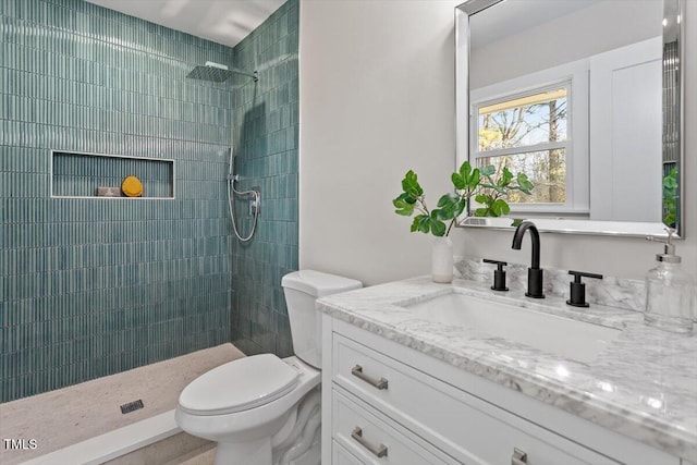 bathroom featuring vanity, tiled shower, and toilet