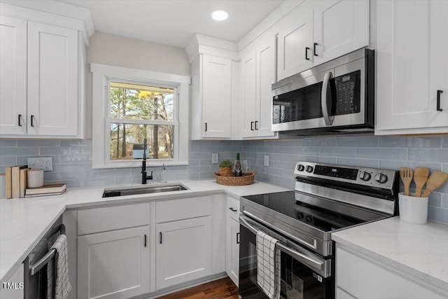 kitchen featuring sink, white cabinetry, light stone counters, stainless steel appliances, and backsplash