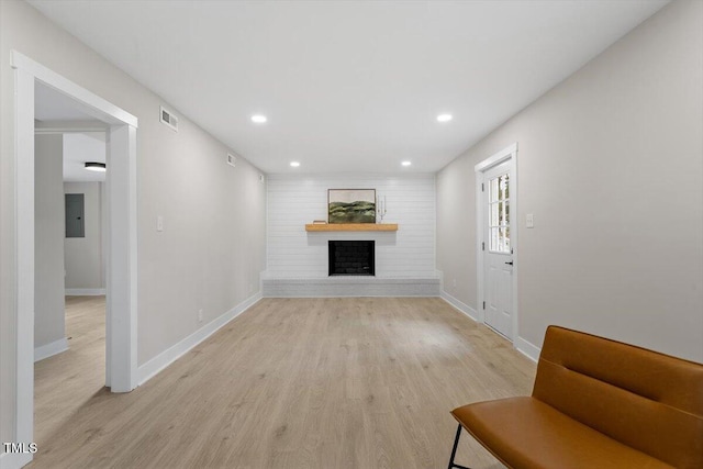 living room with a fireplace, electric panel, and light wood-type flooring