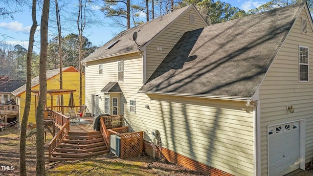 rear view of property featuring a wooden deck and a garage