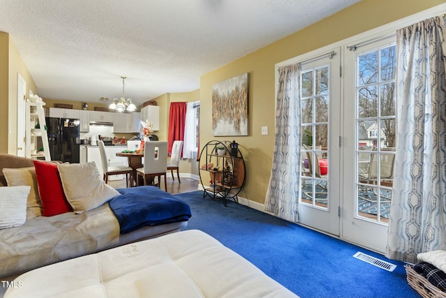 living room featuring carpet, a notable chandelier, and a textured ceiling