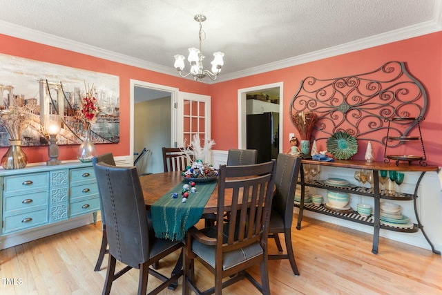 dining space featuring light hardwood / wood-style floors, a chandelier, a textured ceiling, and ornamental molding