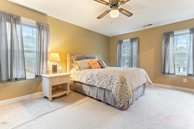 carpeted bedroom with multiple windows and ceiling fan