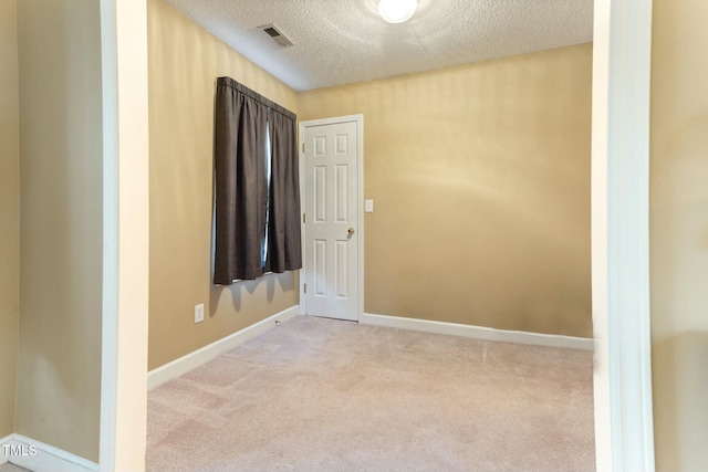 unfurnished room with light colored carpet and a textured ceiling