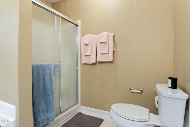 bathroom featuring tile patterned floors, toilet, and a shower with shower door