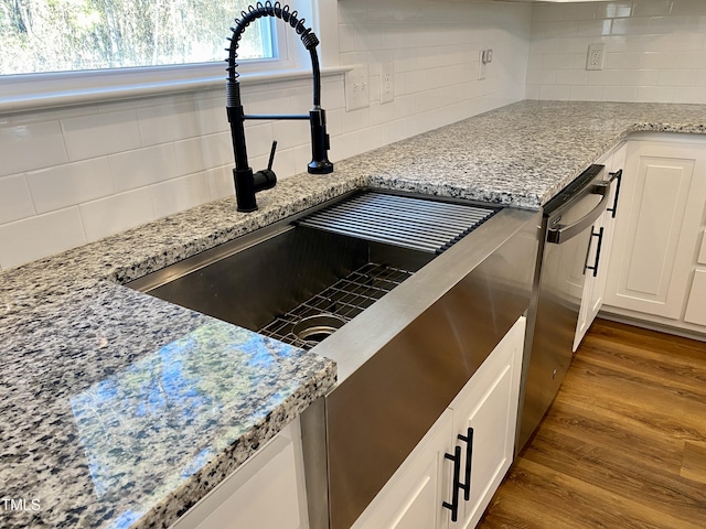 room details with hardwood / wood-style floors, tasteful backsplash, white cabinetry, and light stone counters