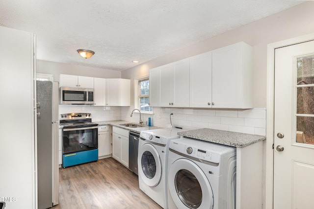 laundry area with hardwood / wood-style flooring, sink, separate washer and dryer, and a textured ceiling