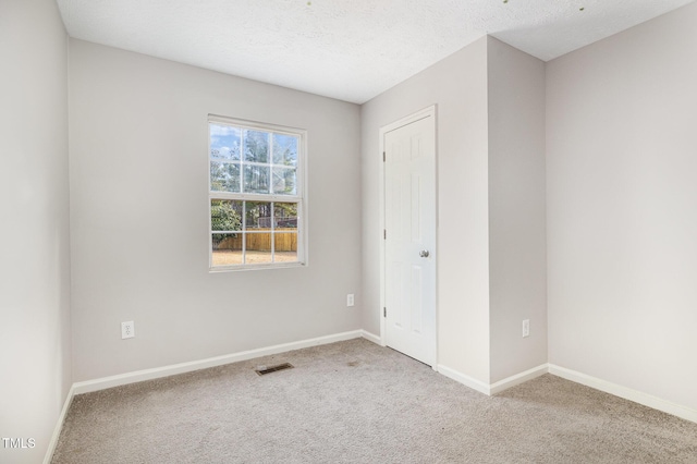 empty room with light carpet and a textured ceiling