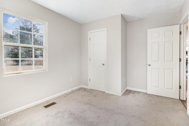 unfurnished bedroom with light colored carpet and a textured ceiling