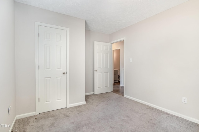 unfurnished bedroom with a textured ceiling and light colored carpet