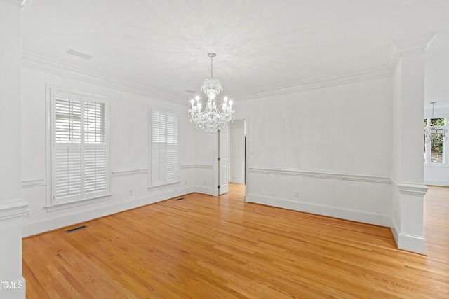 spare room featuring light wood-type flooring, ornamental molding, and an inviting chandelier