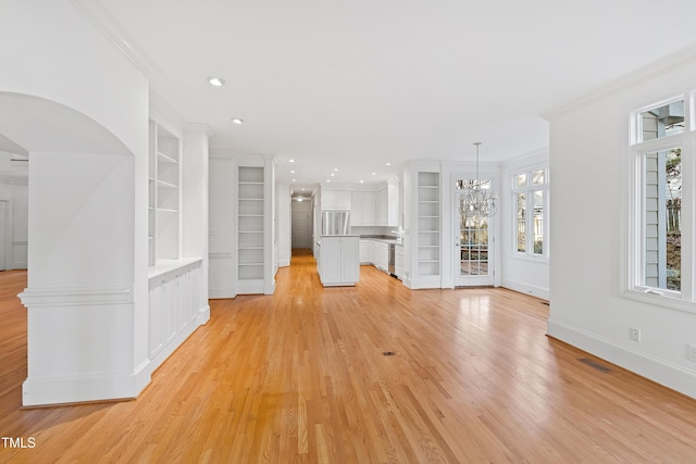 unfurnished living room with light hardwood / wood-style flooring, built in features, crown molding, and a notable chandelier