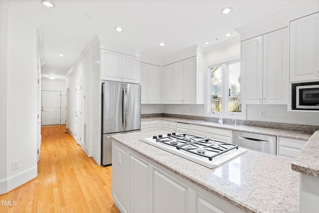 kitchen with white gas cooktop, ornamental molding, built in microwave, white cabinetry, and stainless steel refrigerator