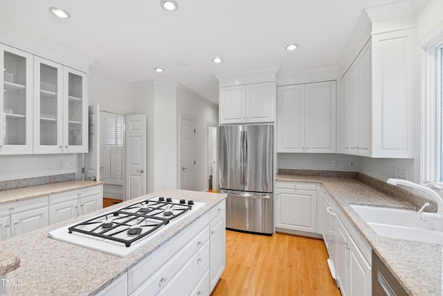 kitchen with stainless steel fridge, sink, white cabinetry, and white gas stovetop