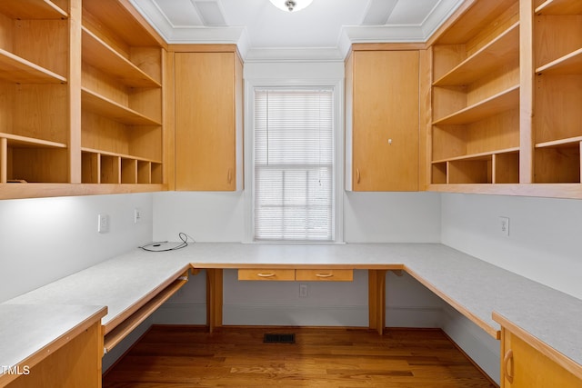 unfurnished office with dark hardwood / wood-style flooring, built in desk, ornamental molding, and a healthy amount of sunlight