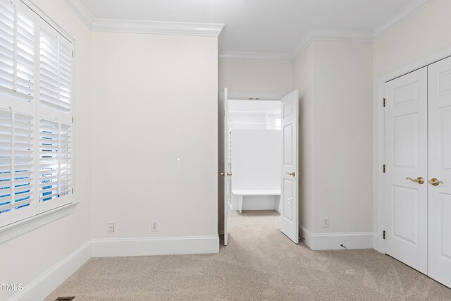 unfurnished bedroom featuring light carpet and crown molding