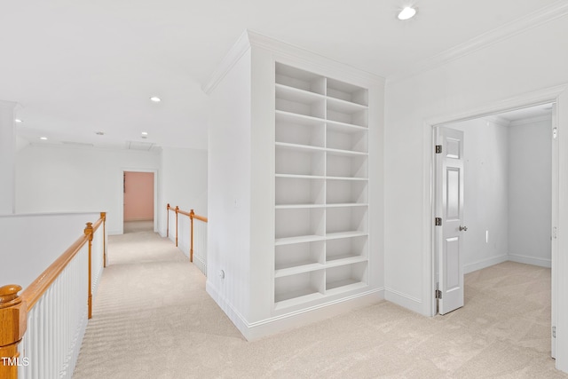 hallway with built in shelves, light carpet, and ornamental molding