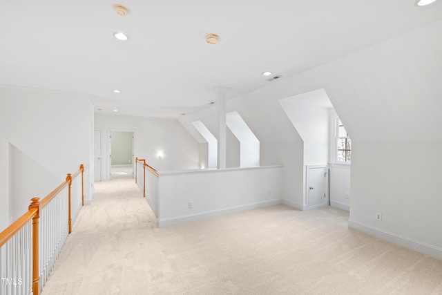 additional living space featuring light colored carpet and vaulted ceiling