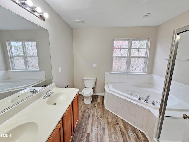 bathroom with wood-type flooring, vanity, toilet, and a healthy amount of sunlight