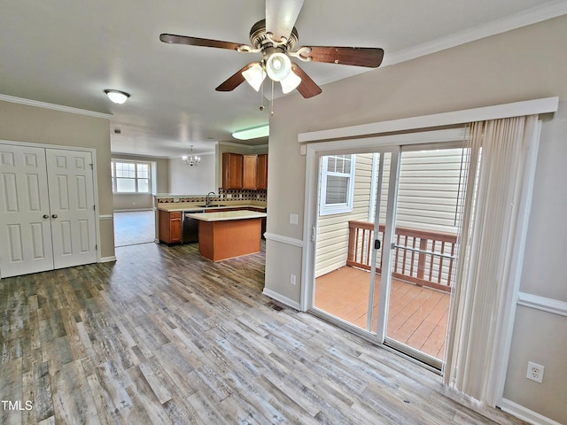 kitchen featuring sink, light hardwood / wood-style flooring, backsplash, kitchen peninsula, and ceiling fan with notable chandelier