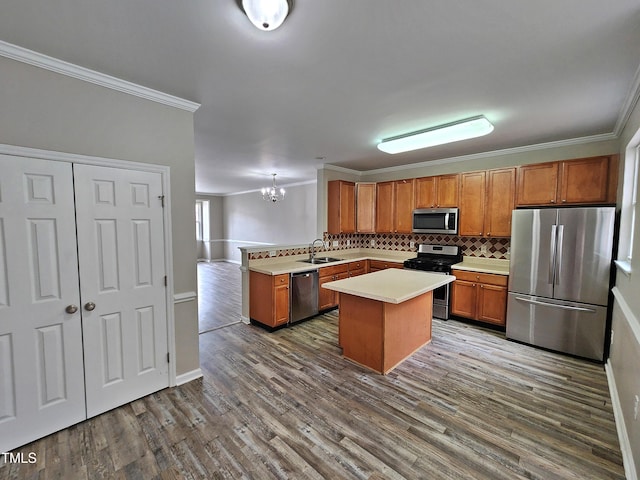 kitchen with sink, stainless steel appliances, an inviting chandelier, kitchen peninsula, and ornamental molding